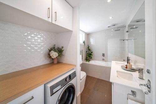 a white bathroom with a washing machine and a sink at Marseille Glenelg - Firepit BBQ Central in Glenelg