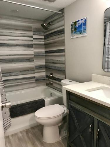 a bathroom with a toilet and a tub and a sink at Beach Living at its Best! in Cocoa Beach