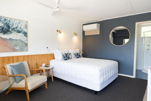 1 dormitorio con cama, silla y espejo en Motel Maclean, en Maclean