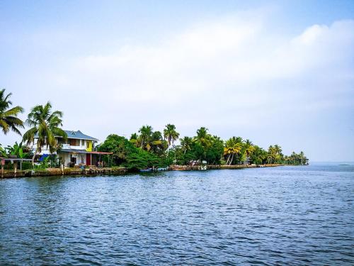 a large body of water with houses and palm trees at Green valley Alleppey in Alleppey