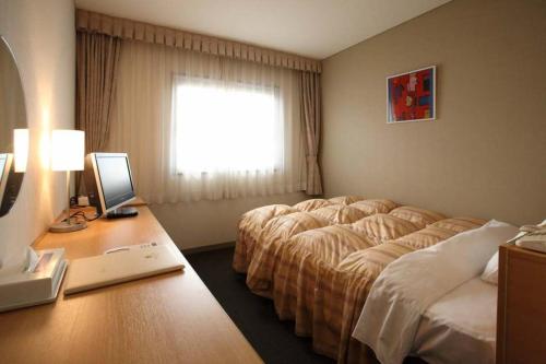 a hotel room with a bed and a desk with a computer at Okura Hotel Marugame in Marugame