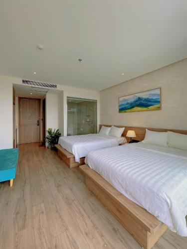 two beds in a large room with wooden floors at Mia Apec Mandala Phú Yên in Tuy Hoa