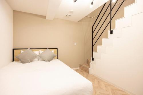 a bedroom with a white bed and a staircase at Retaw Hills WASEDA in Tokyo