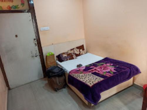 ein kleines Schlafzimmer mit einem Bett mit einer lila Decke in der Unterkunft HOTEL THAKUR JI,Bhopal in Bhopal