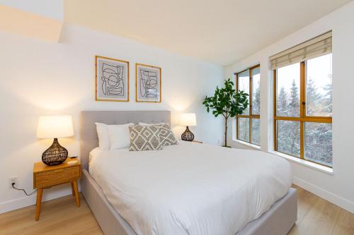 a white bedroom with a bed and two lamps at 600 SQFT 1 Bed 1 Bath Mountain View Suite at Cascade Lodge in Whistler Village Sleeps 4 in Whistler
