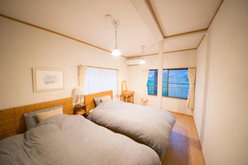 1 dormitorio con 2 camas y ventana en おもや彩OmoyaSai-天然温泉付き貸別荘1棟貸し, en Kirishima