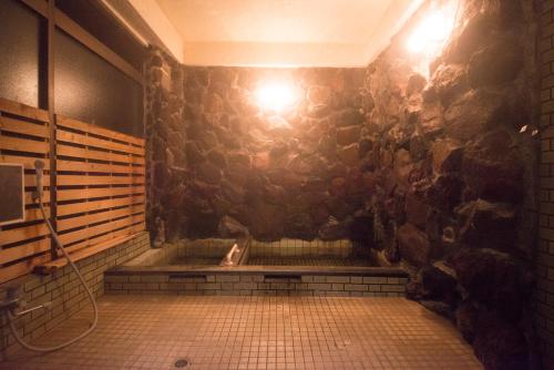 y baño con ducha y pared de piedra. en おもや彩OmoyaSai-天然温泉付き貸別荘1棟貸し, en Kirishima