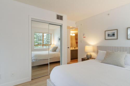 a white bedroom with a bed and a mirror at 900 SQFT 2 Bed 2 Bath Renovated Suite at Cascade Lodge in Whistler Village Sleeps 6 in Whistler
