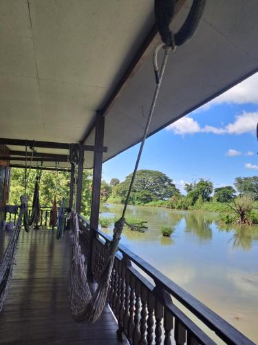 东德岛Riverside Bungalow Don Det的带吊床的门廊,眺望着河流