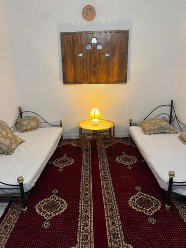 a room with two beds and a table on a rug at L'Oasis à Tozeur in Tozeur