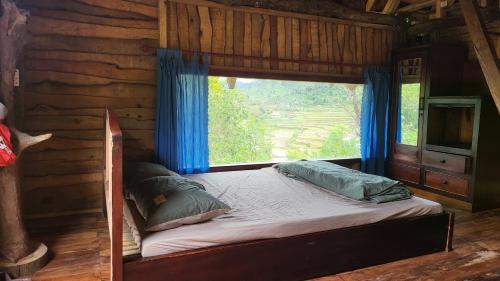 a bed with a window in a log cabin at KONKE RUỘNG FARMSTAY in Kon Von Kla