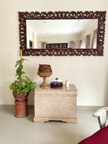 a mirror on a wall above a table with a vase at Kandjeng Puri Kailas Canggu in Sempidi