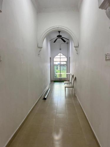 a hallway with white walls and a ceiling fan at D' Flora Inn in Kota Bharu