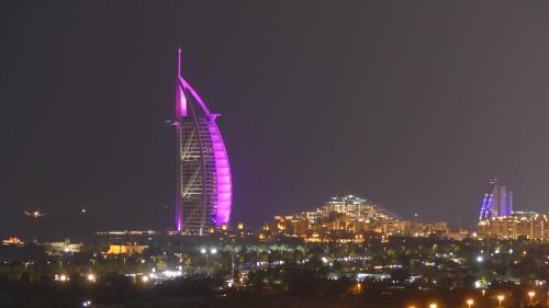 a tall building lit up in purple at night at Apartment in Al Sufouh 1st - Comfortable Home with 5 iconic views in Dubai