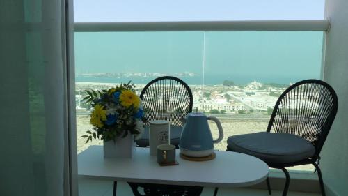 a table with a vase of flowers and two chairs at Apartment in Al Sufouh 1st - Comfortable Home with 5 iconic views in Dubai
