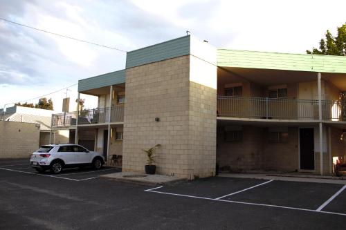 un bâtiment avec une voiture garée sur un parking dans l'établissement Bendigo Motor Inn, à Bendigo