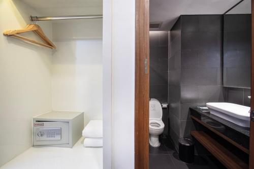 a bathroom with a toilet and a sink at Golden Tulip Essential Makassar in Makassar