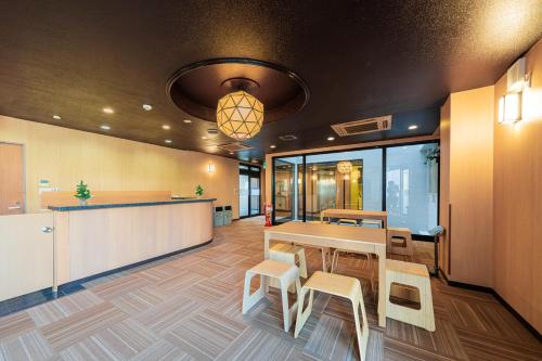 TOKYO E JOY INN （East Nipoori Branch） في طوكيو: مكتب فيه طاولة وكراسي وكاونتر