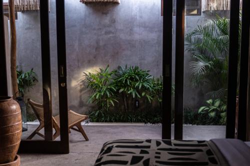 a room with a glass door with plants in it at Kano Twin in Canggu