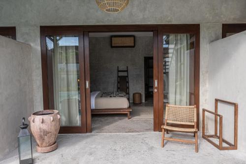 a room with a bedroom with a bed and glass doors at Kano Twin in Canggu