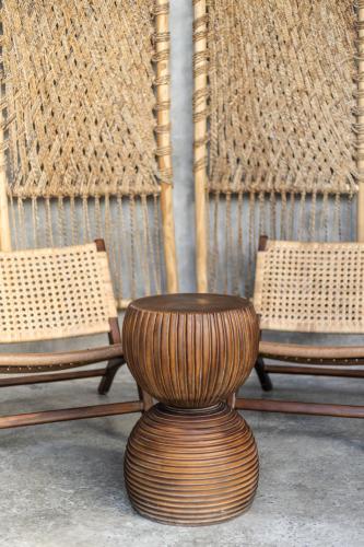 a wooden stool sitting next to two wicker chairs at Kano Twin in Canggu