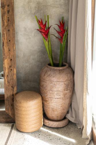 a vase with red flowers in it next to a stool at Kano Twin in Canggu