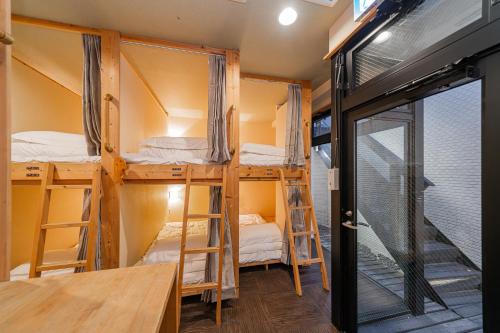 a room with four bunk beds and a table at TOKYO E JOY INN （East Nipoori Branch） in Tokyo