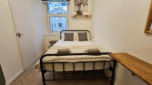 uma pequena cama num pequeno quarto com uma janela em Bros Inn Hotel em Londres