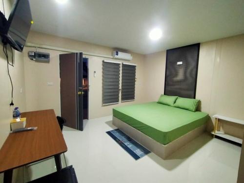 Un dormitorio con una cama verde y una mesa en ริมธารริเวอร์เพลส en Surat Thani
