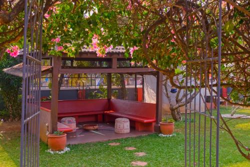 a red bench in a gazebo in a garden at Skylark Resort in Colva