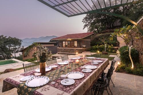 a long table with plates and dishes on it at SaffronStays Sunkissed - 2 Bedroom Infinity Pool Villa in Mulshi in Mulshi