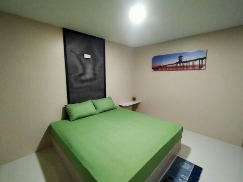 a small bedroom with a green bed in a room at ริมธารริเวอร์เพลส in Surat Thani