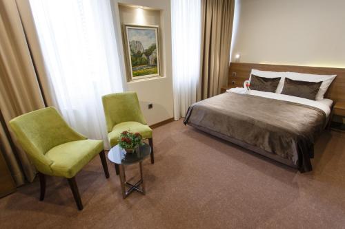 a hotel room with a bed and two chairs at Hotel Kragujevac in Kragujevac