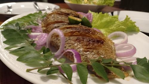 a plate of food with meat and vegetables on a table at The Villa Hush in Hikkaduwa