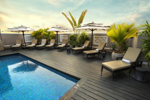 a pool with chairs and umbrellas on a deck at Hilton Garden Inn, Trivandrum in Trivandrum