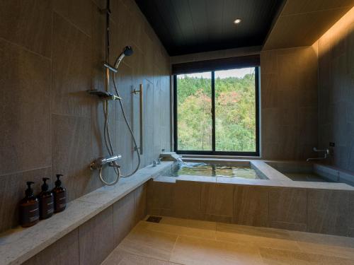 a bathroom with a tub and a shower with a window at Rakuten STAY VILLA Nikko in Nikko