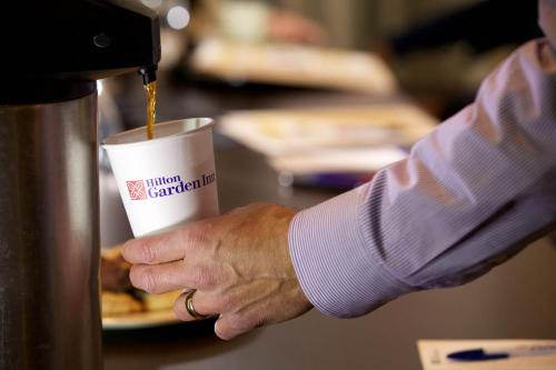 a person is holding a cup of coffee at Hilton Garden Inn, Trivandrum in Trivandrum