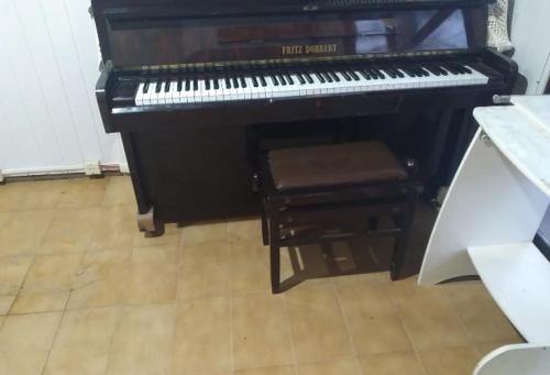 B & B Hostel Ingleses في فلوريانوبوليس: بيانو أسود مع كرسي وكرسي