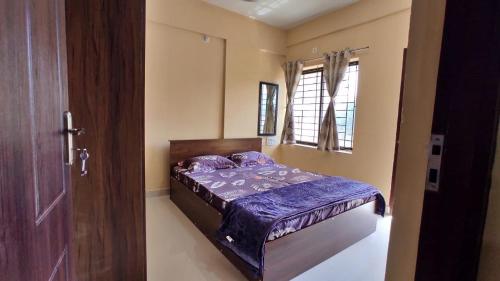 sypialnia z łóżkiem z fioletową pościelą i oknem w obiekcie UDUPI G01 HOMESTAY w mieście Udupi