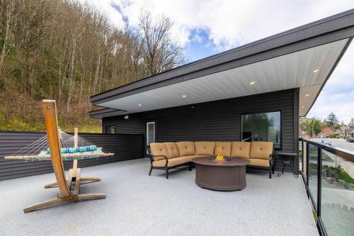 a backyard patio with a couch and a table at A Mountain Retreat with Views, Hot Tub & AC in Chilliwack