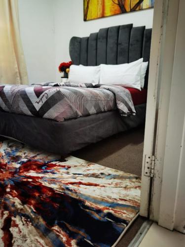 a bedroom with a bed with a black headboard at Galaxy Sleep And Go Rooms Goodwood in Cape Town
