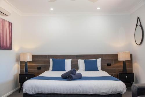 a bedroom with a large bed with blue pillows at Matilda Motor Inn in Dubbo