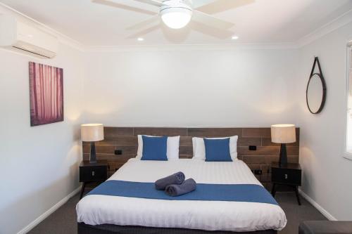 a bedroom with a large bed with blue pillows at Matilda Motor Inn in Dubbo