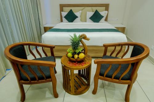 a bedroom with a bed and two chairs and a table with fruit at The Heartland Business Hotel, Trivandrum in Trivandrum
