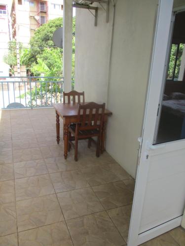 a porch with a wooden table and a chair at Residence Kathyly in Diego Suarez