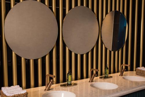 a bathroom with three sinks and two mirrors at Almond Hotel - Adults only in Neve Ilan