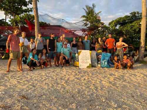 a group of people posing for a picture on the beach at Tribal Huts Community in Daanbantayan