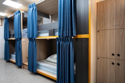 a room with four bunk beds with blue curtains at Carlos Backpacker in Minxiong