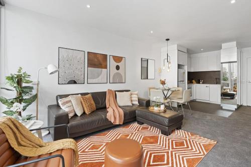 a living room with a black couch and a kitchen at Ultimate Comfort Gem in St Kilda in Melbourne