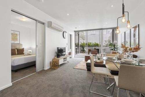 a living room with a dining table and a bedroom at Ultimate Comfort Gem in St Kilda in Melbourne